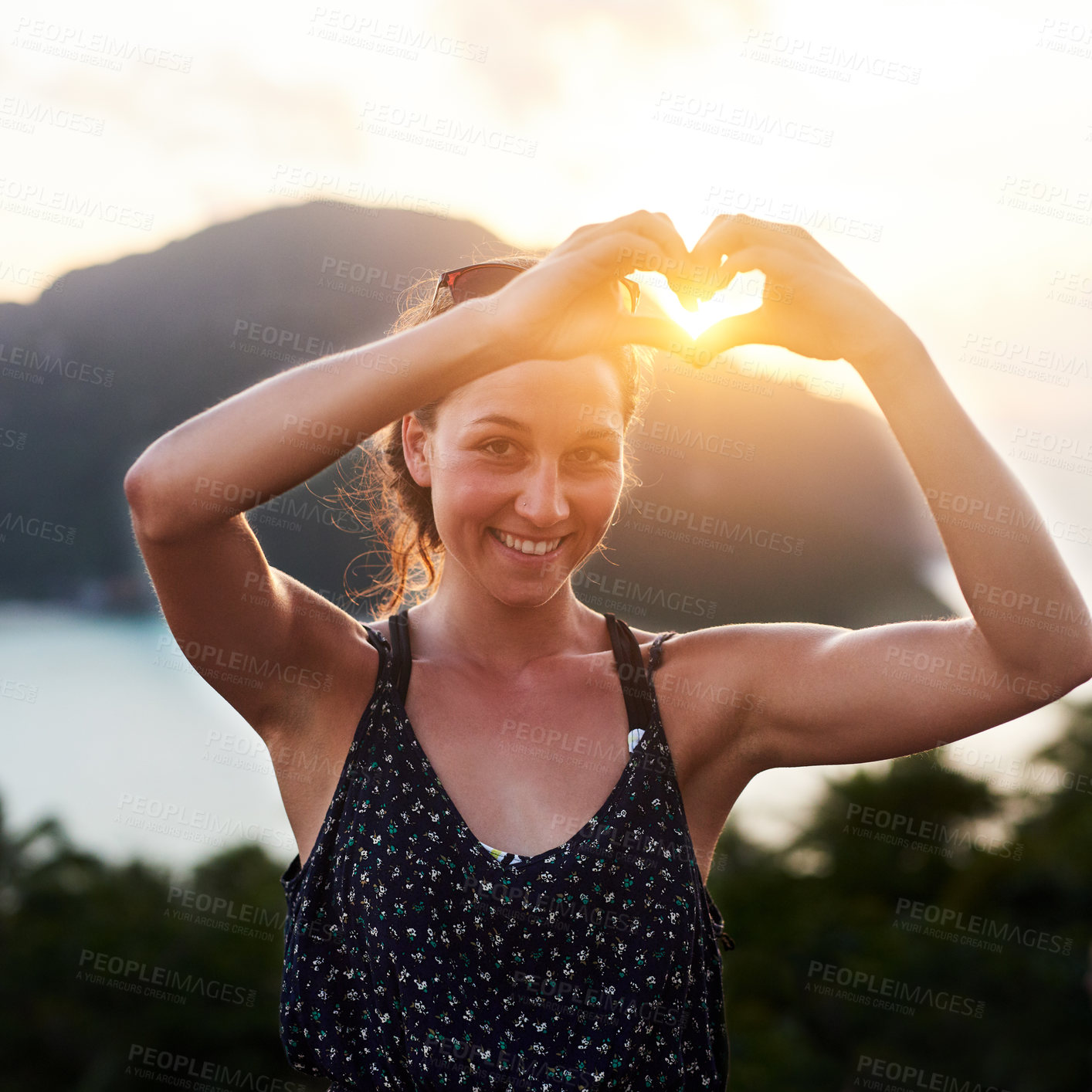 Buy stock photo Portrait of a young woman making a heart gesture outside