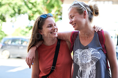 Buy stock photo Cropped shot of two young friends walking around the city together