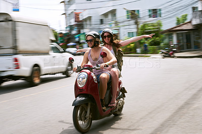 Buy stock photo Shot of a young couple enjoying a scooter ride around the city