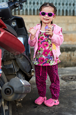 Buy stock photo Portrait of an adorable little girl standing alongside a scooter outside