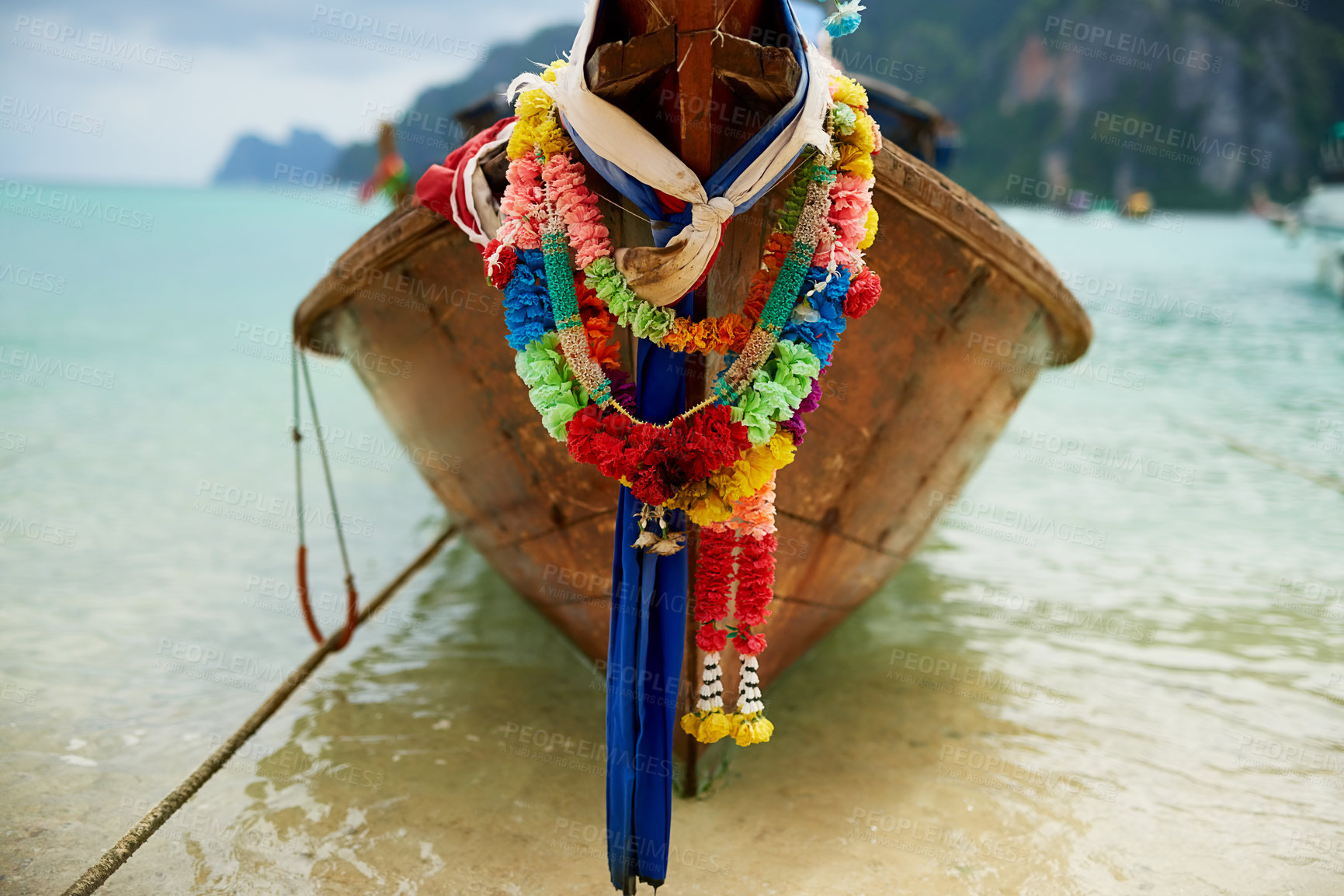 Buy stock photo Shot of a boat on the water with a colorful floral garland hanging from it