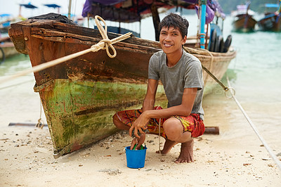 Buy stock photo Portrait of a man from Thailand next to his boat at the water’s edge