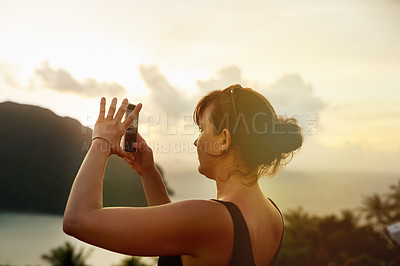 Buy stock photo Shot of a young woman photographing a tropical view with her cellphone while on holiday