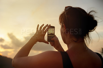 Buy stock photo Shot of a young woman photographing a tropical view with her cellphone while on holiday