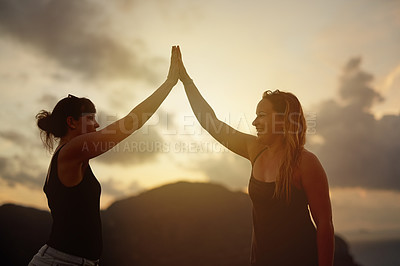 Buy stock photo Shot of two happy young friends high fiving each other at sunset