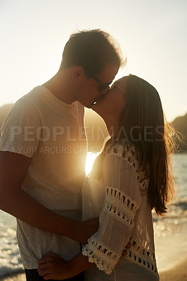 Buy stock photo Shot of an affectionate young couple on the beach at sunset