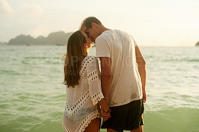 Buy stock photo Rearview shot of an affectionate young couple on the beach at sunset