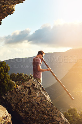 Buy stock photo Shot of a young man standing on a mountain top
