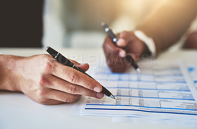 Buy stock photo Closeup shot of two unidentifiable businesspeople going through some paperwork in an office