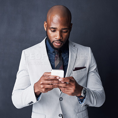 Buy stock photo Studio shot of a businessman using a mobile phone against a gray background