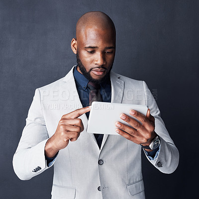 Buy stock photo Studio shot of a businessman using a digital tablet against a gray background