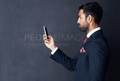 Buy stock photo Studio shot of a young businessman using a mobile phone against a gray background