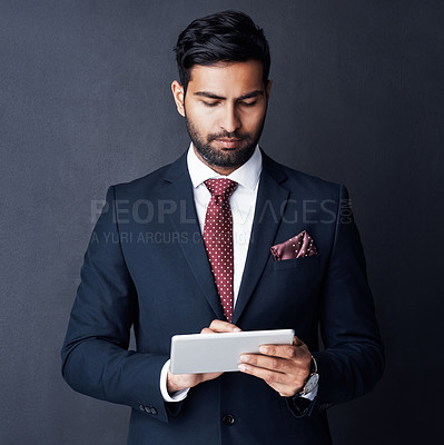 Buy stock photo Serious, business man and tablet in studio, dark background and app for trading, planning or internet research. Corporate broker, indian male trader or focus on digital technology, online and website
