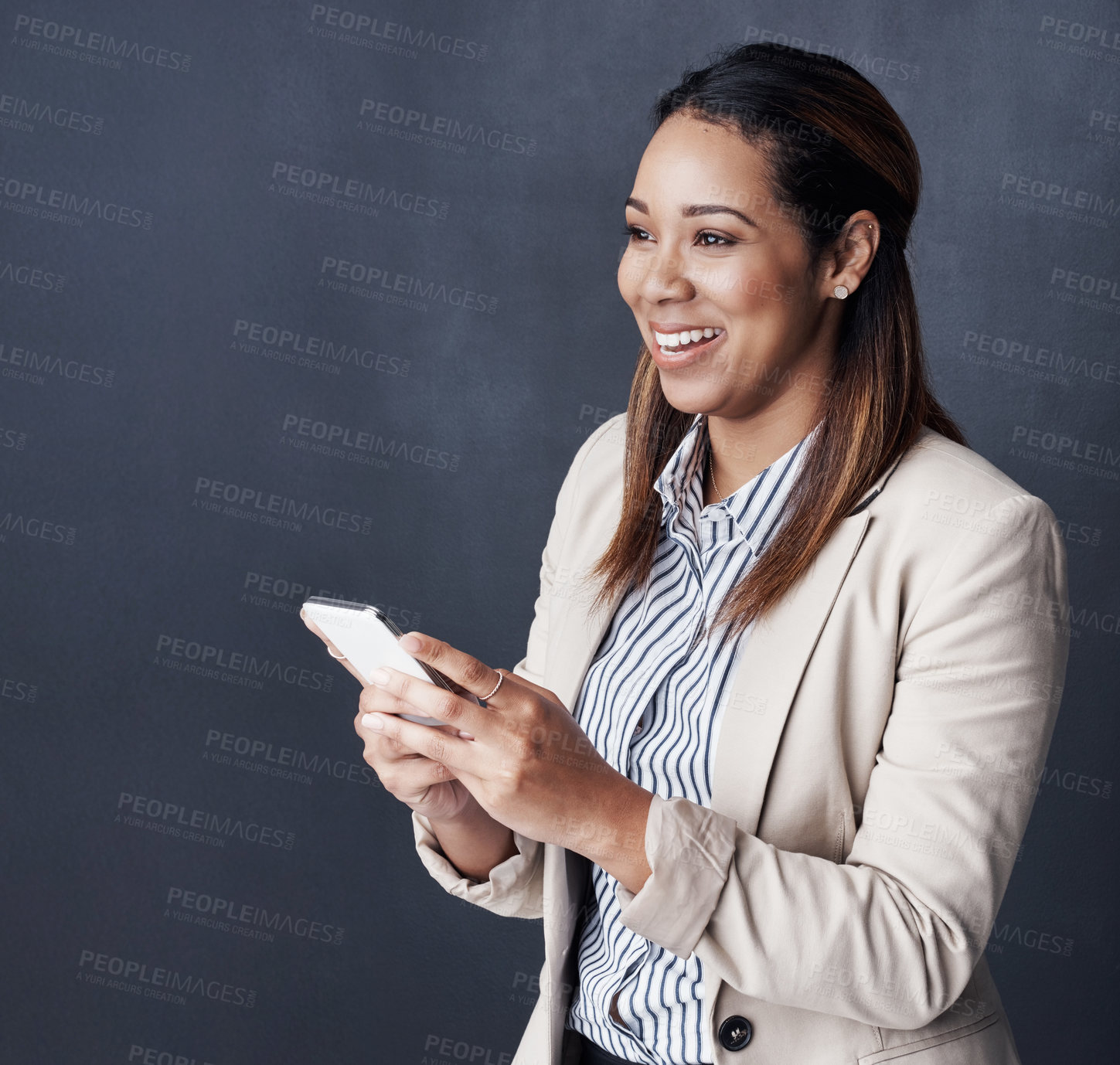 Buy stock photo Studio shot of a young businesswoman using her cellphone against a grey background
