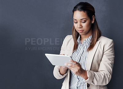 Buy stock photo Studio shot of a young businesswoman using her tablet against a grey background