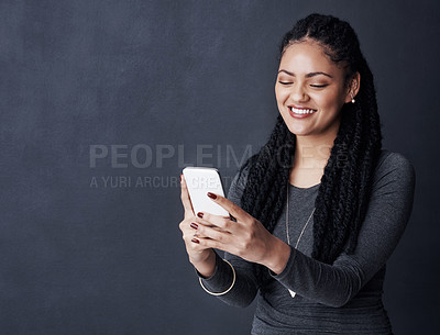 Buy stock photo Studio shot of a young woman using her cellphone against a grey background