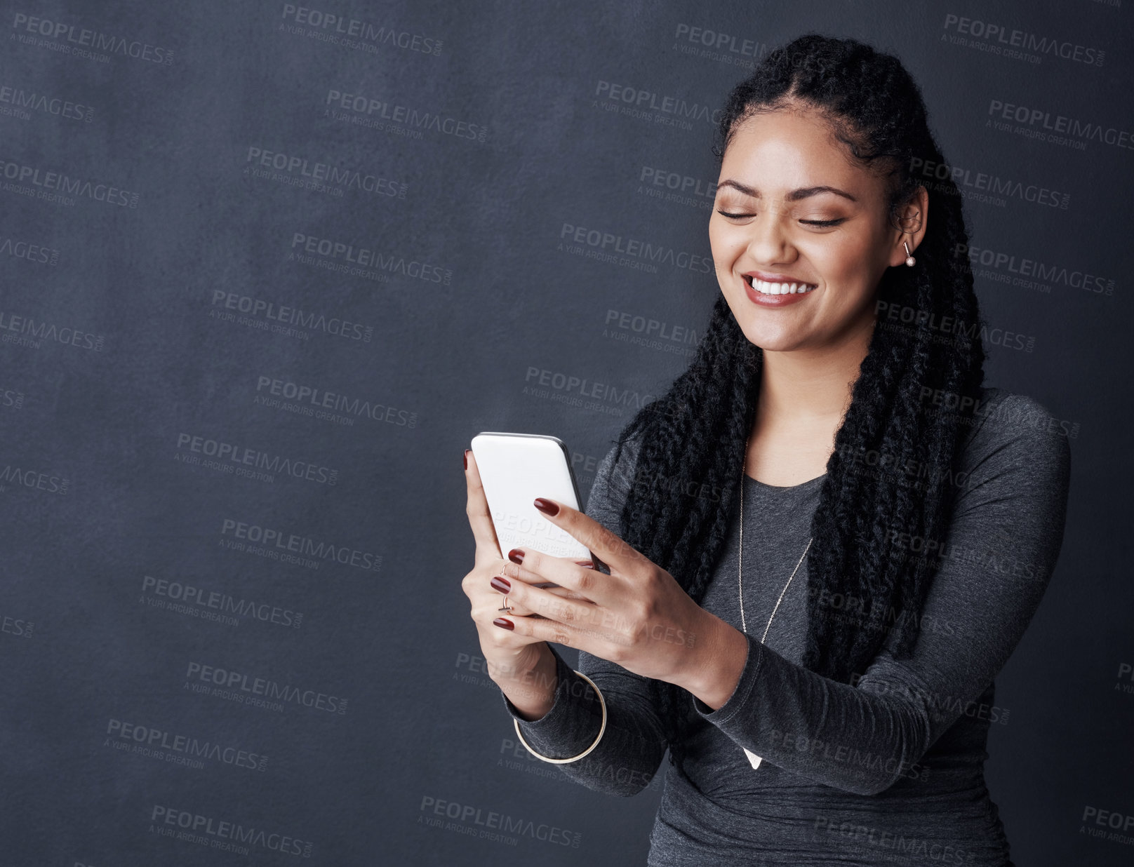 Buy stock photo Studio shot of a young woman using her cellphone against a grey background