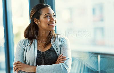 Buy stock photo Shot of an attractive young businesswoman looking out of her office window