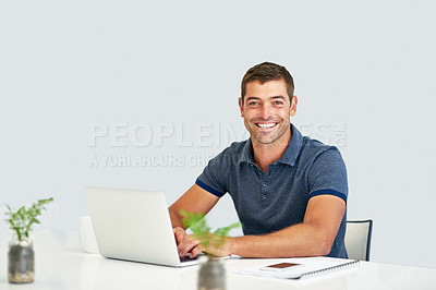 Buy stock photo Portrait of a young man working on a laptop against a white background