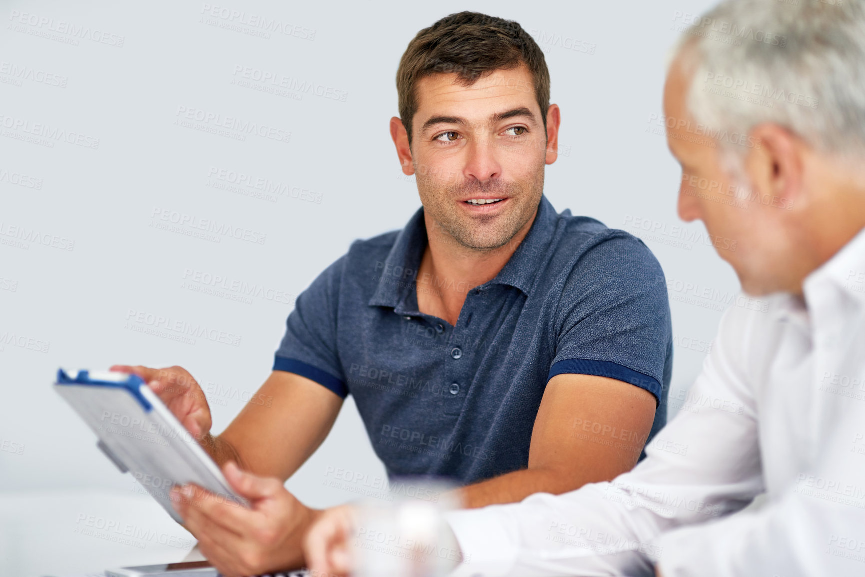 Buy stock photo Cropped shot of two businessmen working together on a digital tablet against a white background