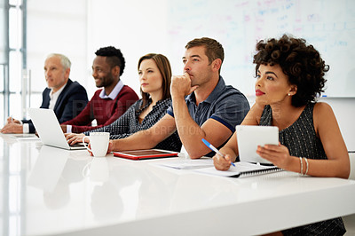Buy stock photo Cropped shot of a group of businesspeople listening to a presentation in an office