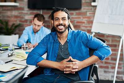 Buy stock photo Portrait of a young designer sitting in an office with his colleagues in the background