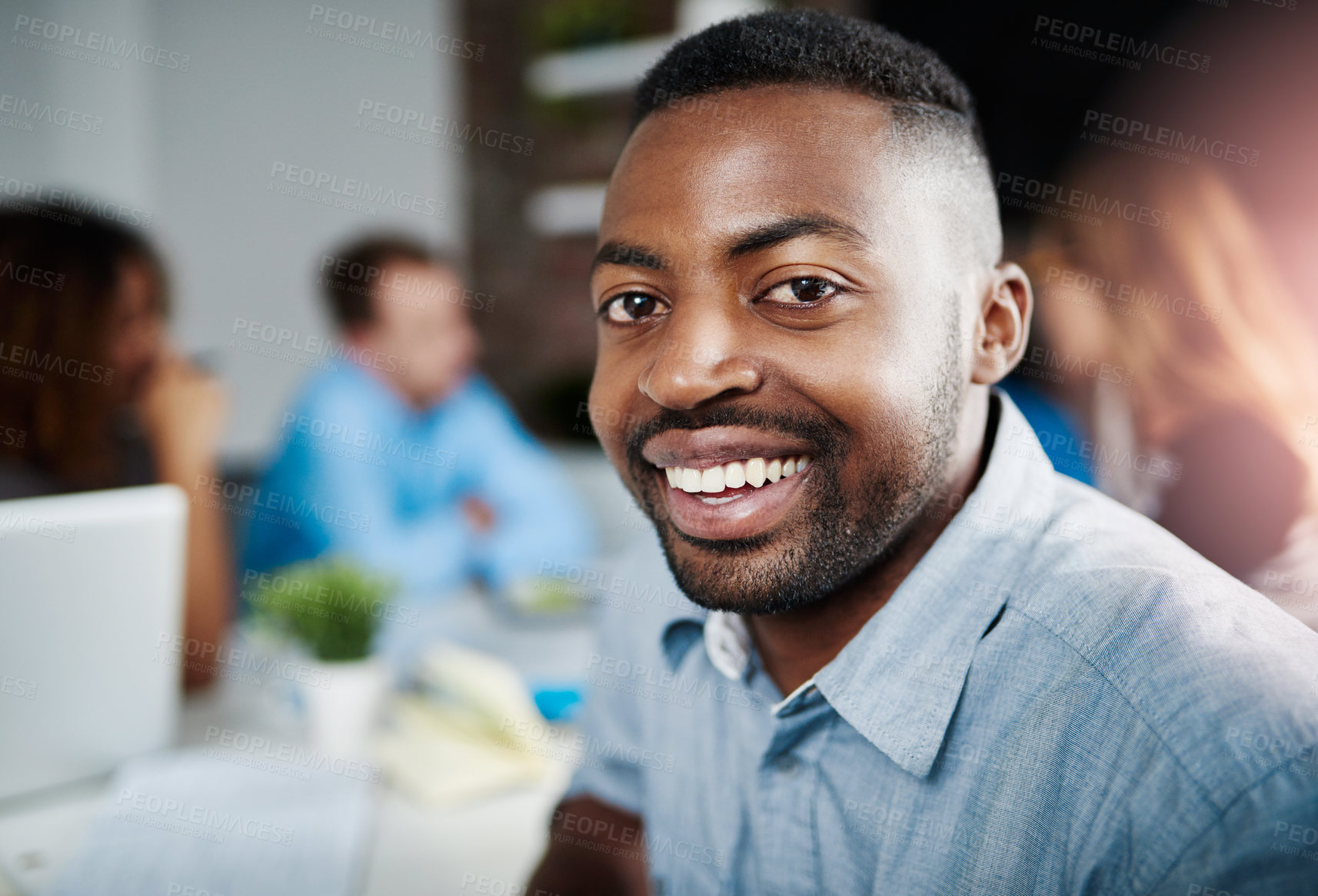 Buy stock photo Portrait of a young designer sitting in an office with his colleagues in the background