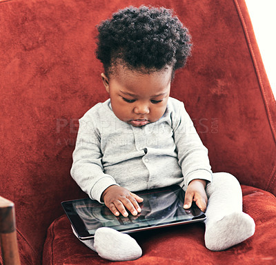 Buy stock photo Shot of a little baby boy sitting in a chair holding a digital tablet