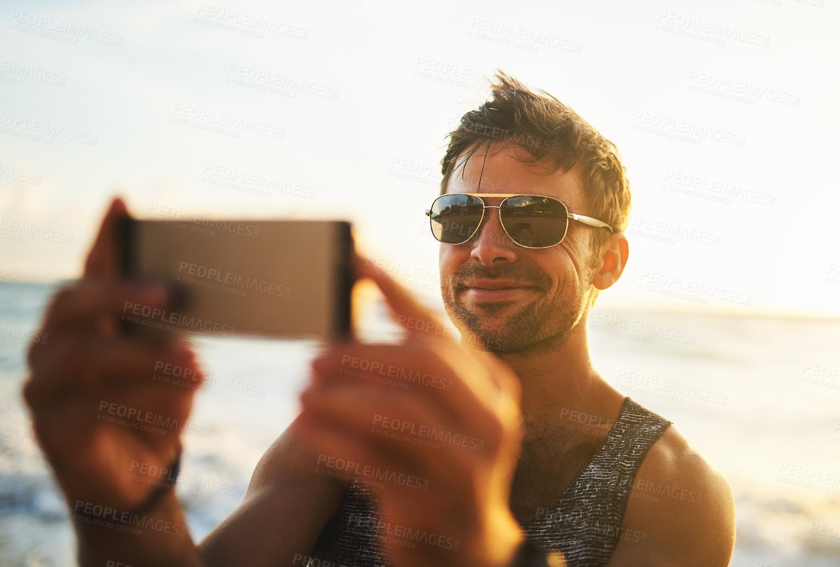 Buy stock photo Cropped shot of a young man taking a selfie at the beach