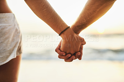 Buy stock photo Cropped shot of a young couple holding hands at the beach