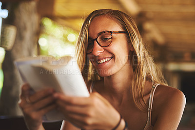 Buy stock photo Cropped shot of a young woman reading a book