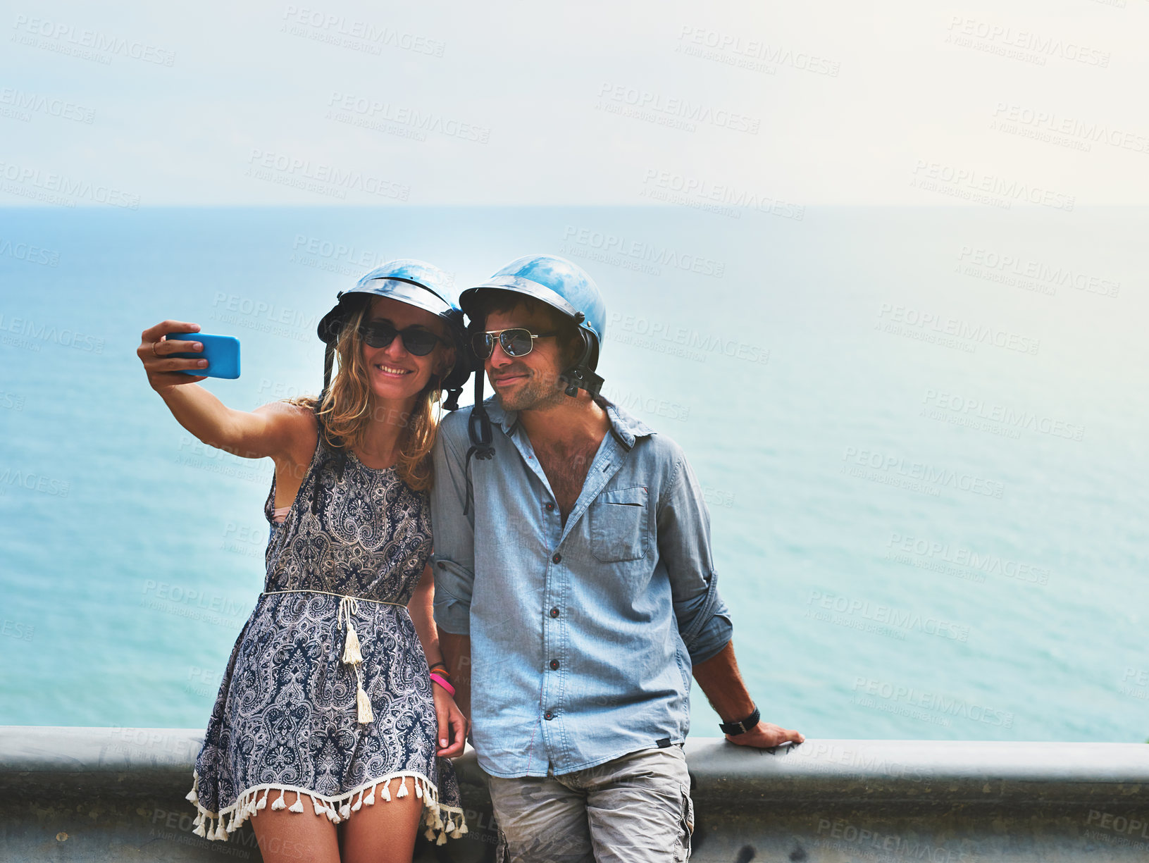 Buy stock photo Selfie, smartphone and couple outdoor with helmet for social media, online digital gallery and profile picture together. Man, woman and mobile with photograph for happy memory and video call by ocean