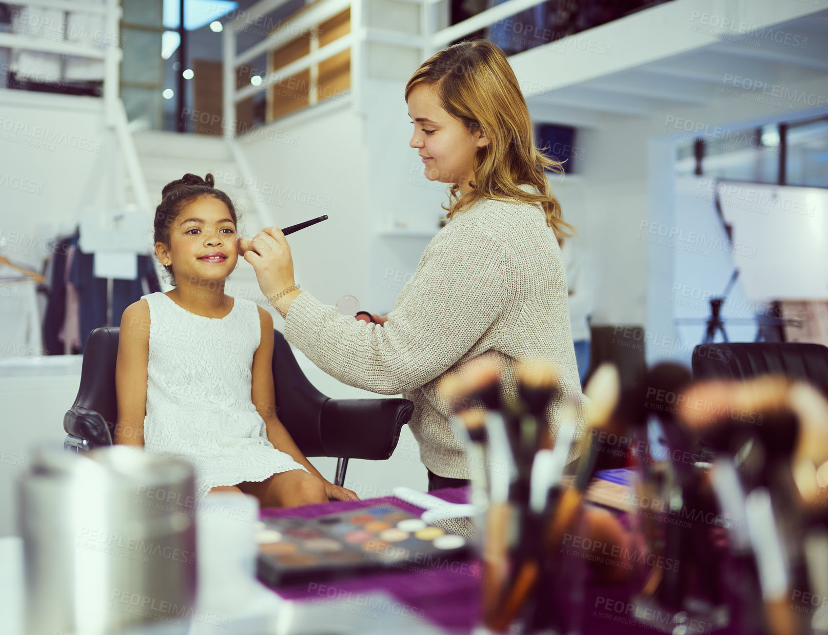 Buy stock photo Shot of a stylist applying makeup to a cute little girl in a dressing room