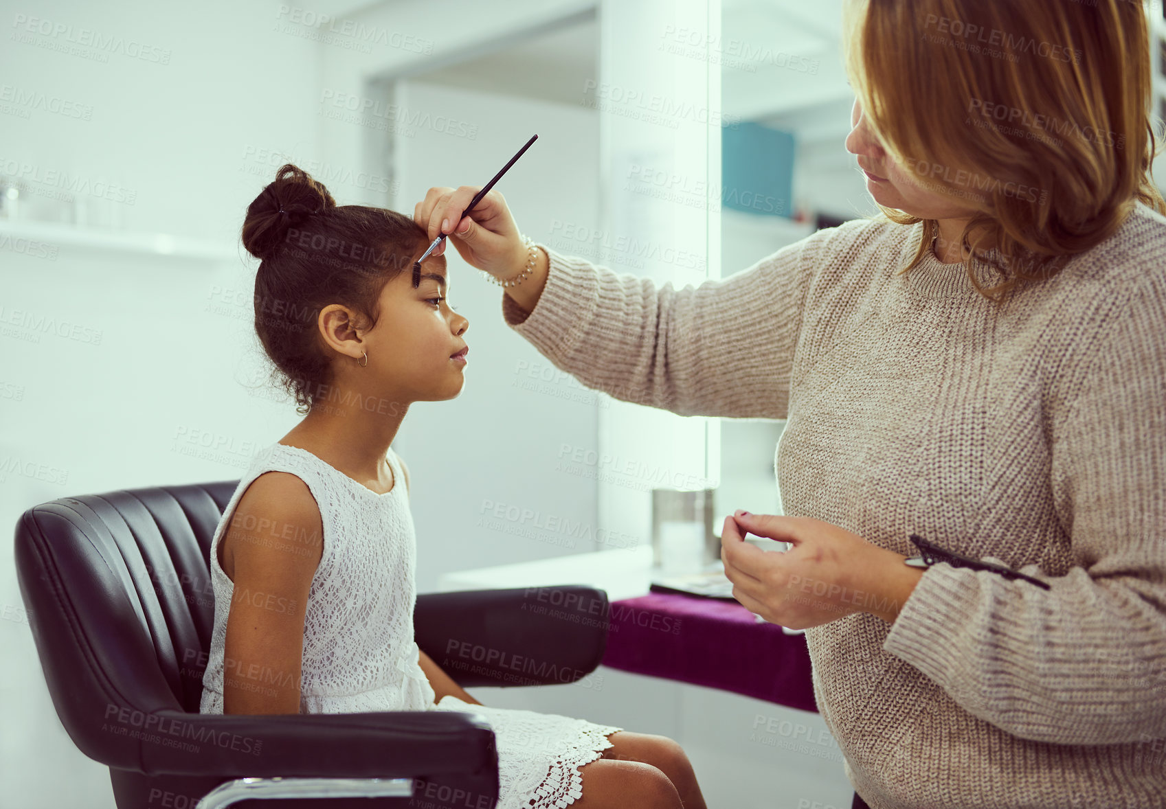 Buy stock photo Backstage, celebrity or makeup with girl and stylist in studio, getting ready behind the scenes. Child model, cosmetics and eyebrow brush with woman on set for creative preparation of talent