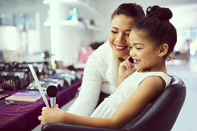 Buy stock photo Shot of a mother helping her cute little girl to apply makeup in a dressing room