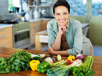 Buy stock photo Portrait of a smiling young woman preparing a meal in her kitchen