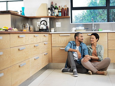 Buy stock photo Shot of a smiling young couple sitting together on their kitchen floor