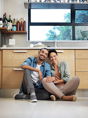 Buy stock photo Portrait of a smiling young couple sitting together on their kitchen floor