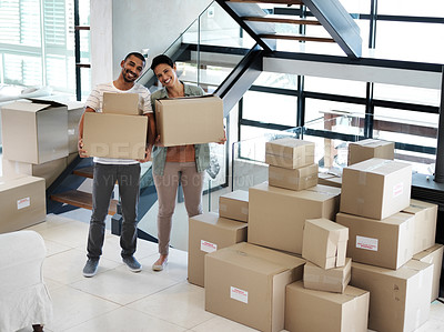 Buy stock photo Portrait of a happy young couple carrying boxes while moving into their new home