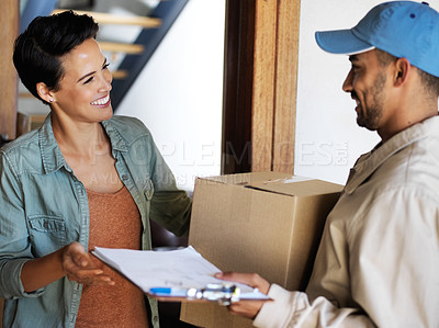 Buy stock photo Shot of a smiling young woman standing at her front door receiving a package from a courier