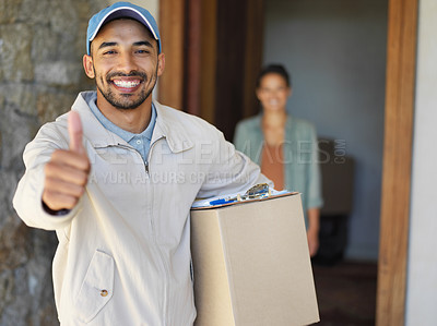 Buy stock photo Portrait of a smiling young courier giving a thumbs up and carrying a package with a customer standing at her front door in the background