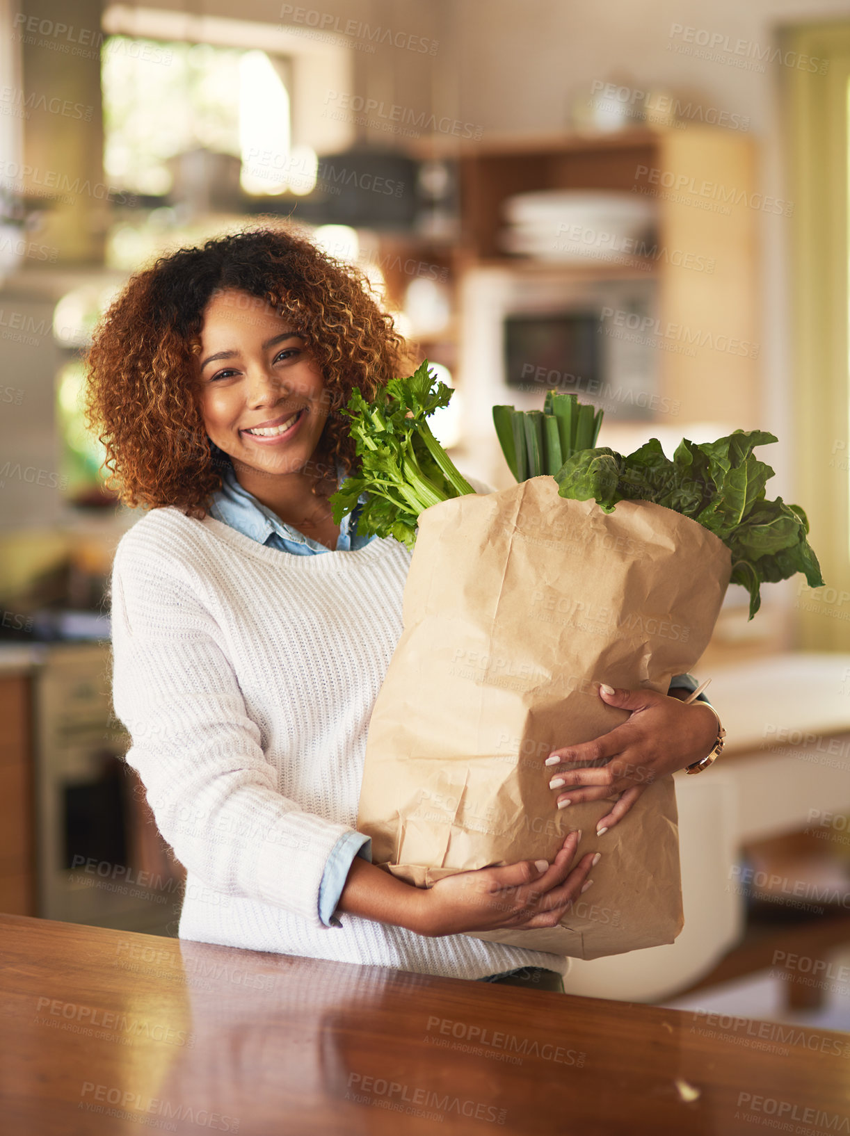 Buy stock photo Portrait of a happy young woman holding a bag full of healthy vegetables at home