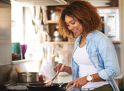 Buy stock photo Shot of a happy young woman preparing a meal on the stove at home