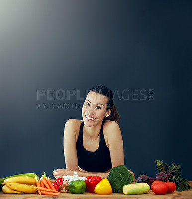 Buy stock photo Studio portrait of an attractive young woman posing with a variety of vegetables on the table