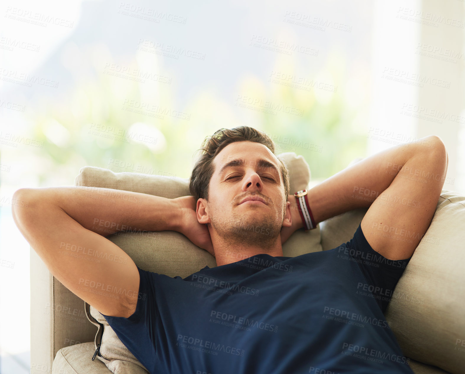 Buy stock photo Cropped shot of a handsome young man resting on his sofa at home