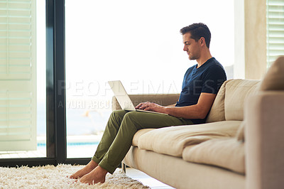 Buy stock photo Full length shot of a handsome young man using his laptop at home