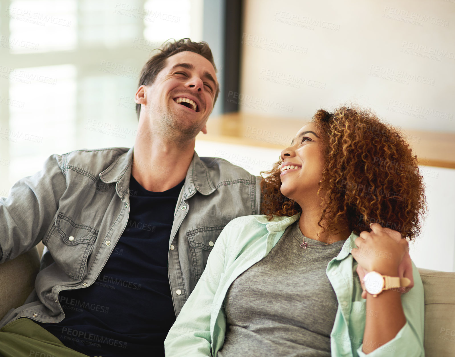 Buy stock photo Love, happy and couple laugh on sofa for bonding, relationship and relaxing people at home. Marriage, man and woman in living room embrace for care, hugging and cheerful for funny joke together