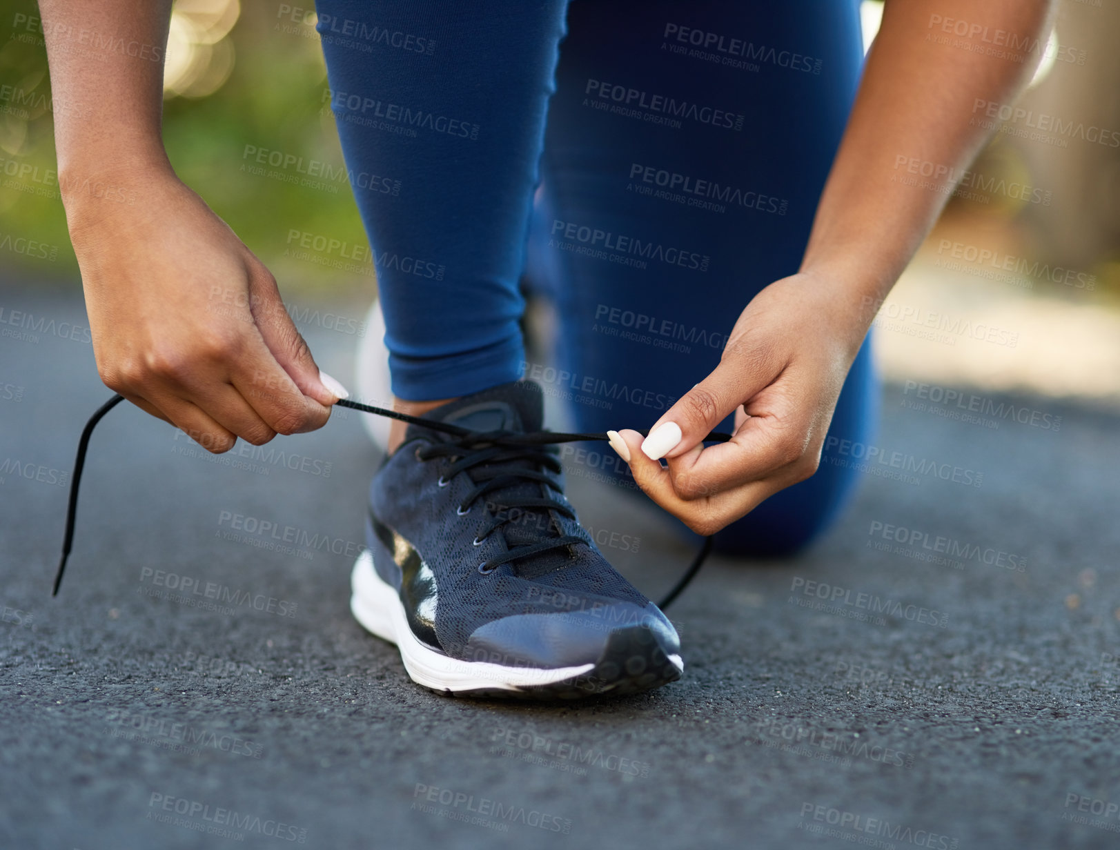 Buy stock photo Cropped shot of an unrecognizable young woman tying her laces before a workout