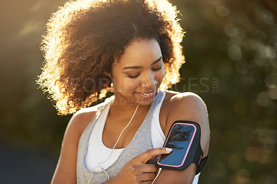 Buy stock photo Shot of an attractive young woman listening to music while exercising outdoors