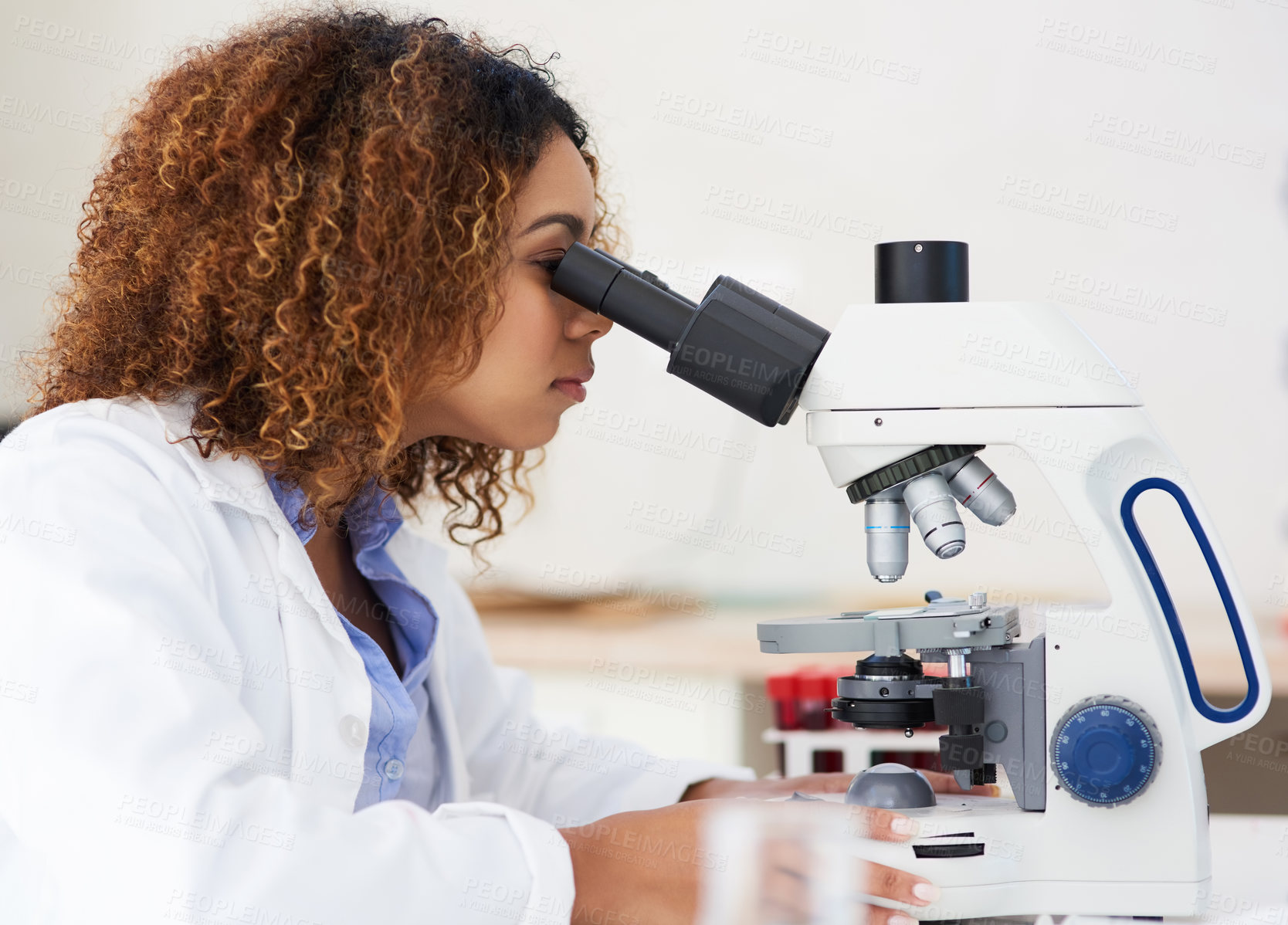 Buy stock photo Cropped shot of a young female scientist looking into a microscope